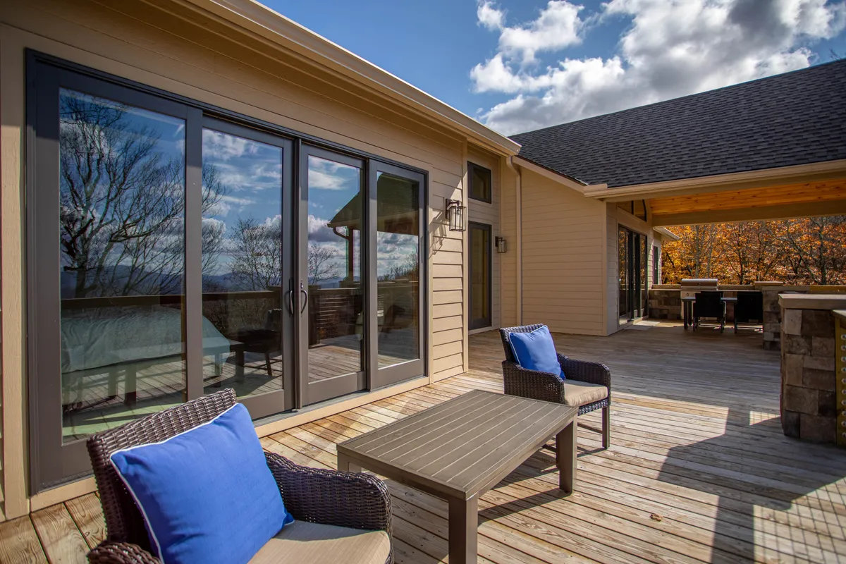 A modern wooden deck featuring comfortable outdoor seating and stylish sliding glass doors provides a seamless transition between indoor leisure and outdoor enjoyment. The inviting setup suggests space for relaxation or extending game nights into the open air.