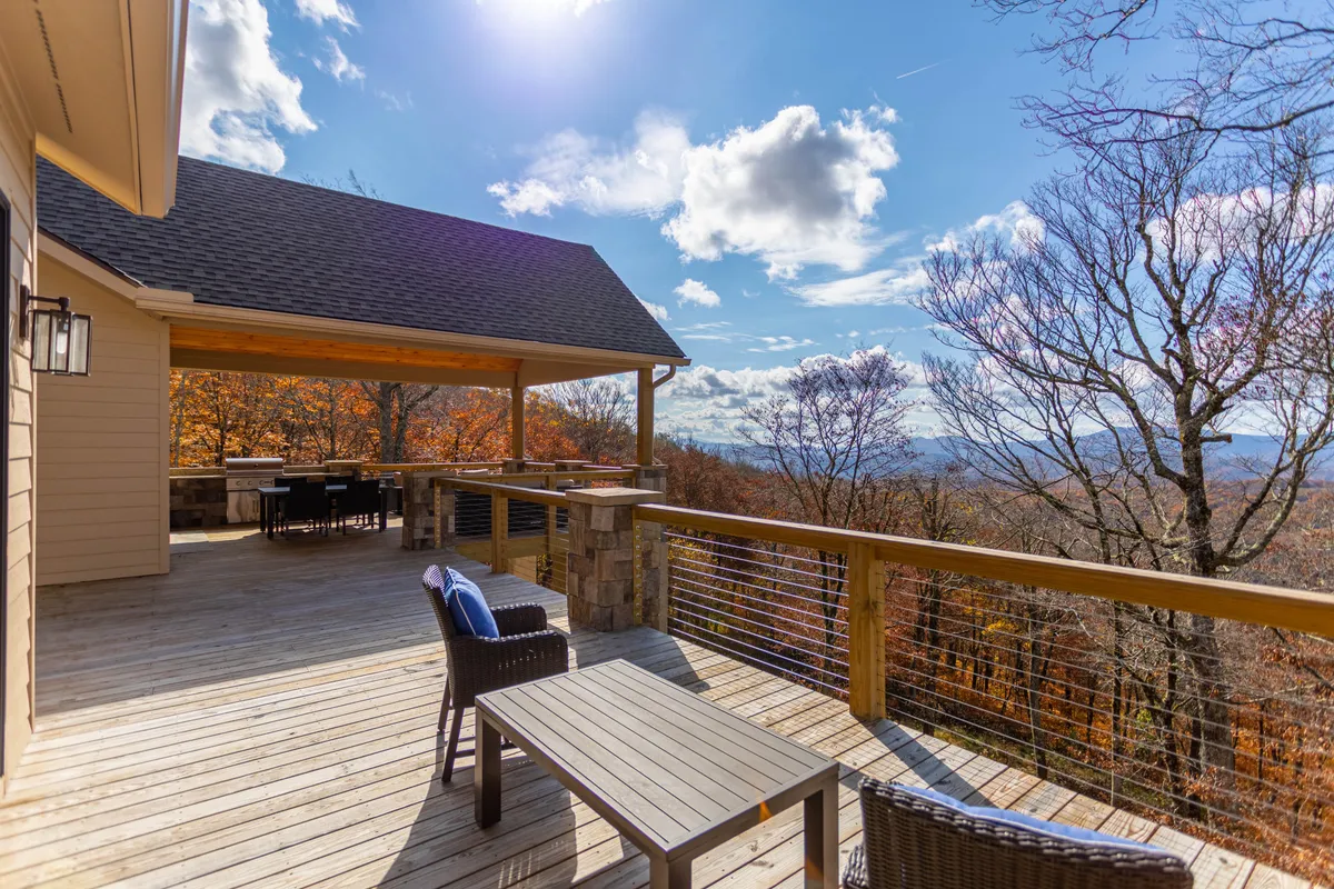 An exterior shot of a spacious deck with outdoor seating, looking out over rolling mountains and a dramatic sky. The scene radiates tranquility and offers a sense of openness, perfect for guests wishing to decompress and take in the High Country's natural beauty.