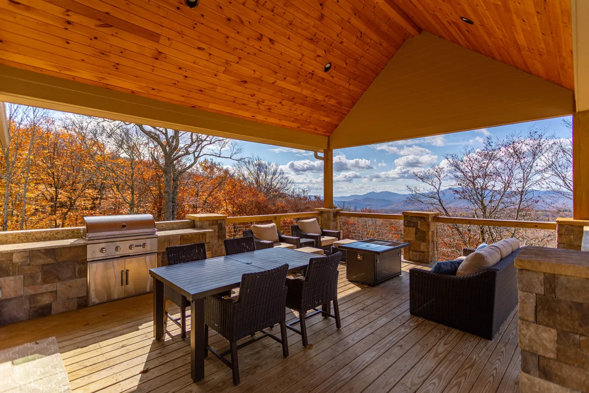 This exterior image captures a covered outdoor kitchen and dining area, complete with a built-in grill, outdoor dining table, lounge seating, and panoramic mountain views. The setting is inviting, ready for al fresco feasts and social gatherings.